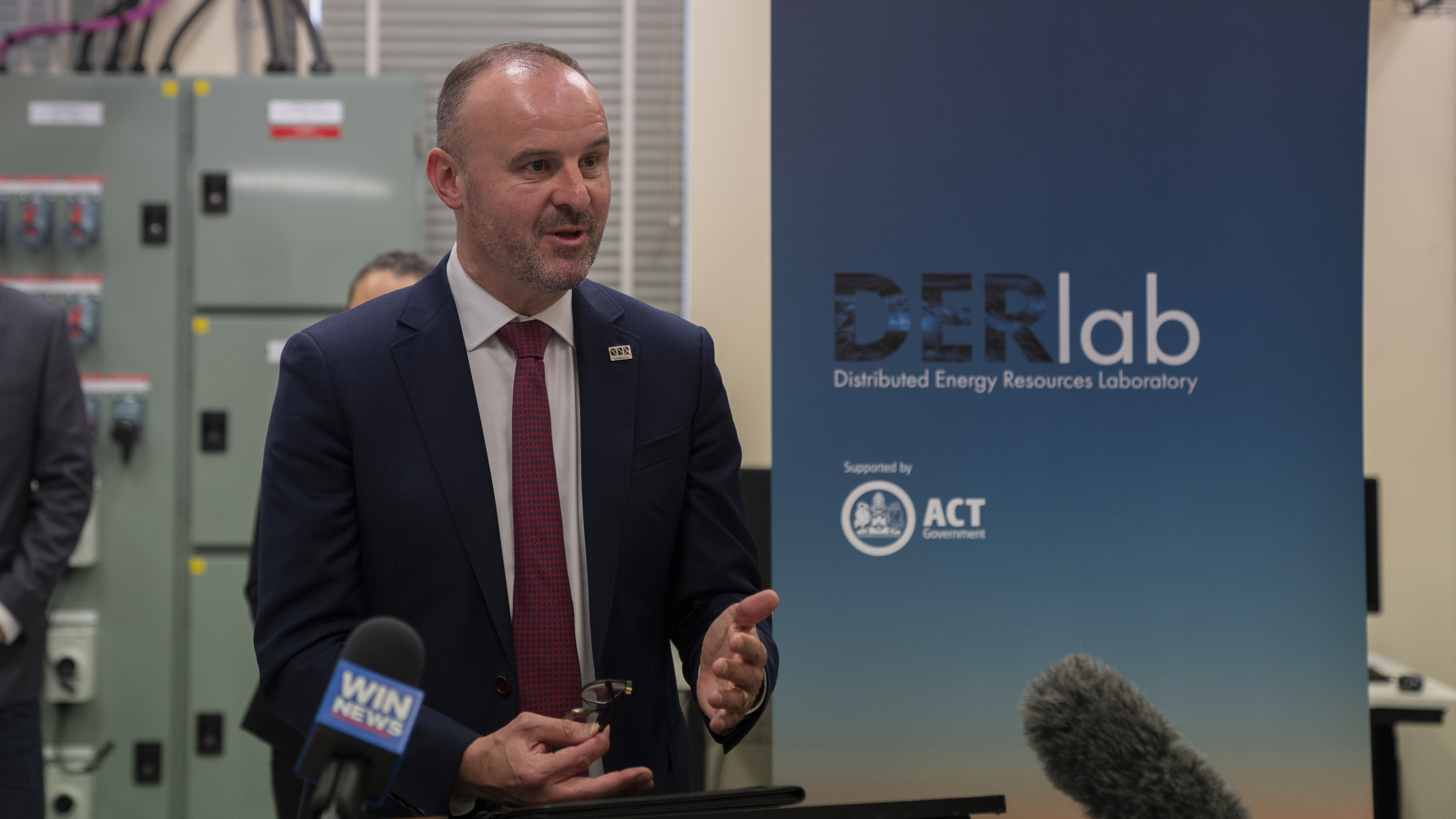 Chief Minister Andrew Barr stands in front of a &#039;DER Lab&#039; banner, and speaks at a lectern.
