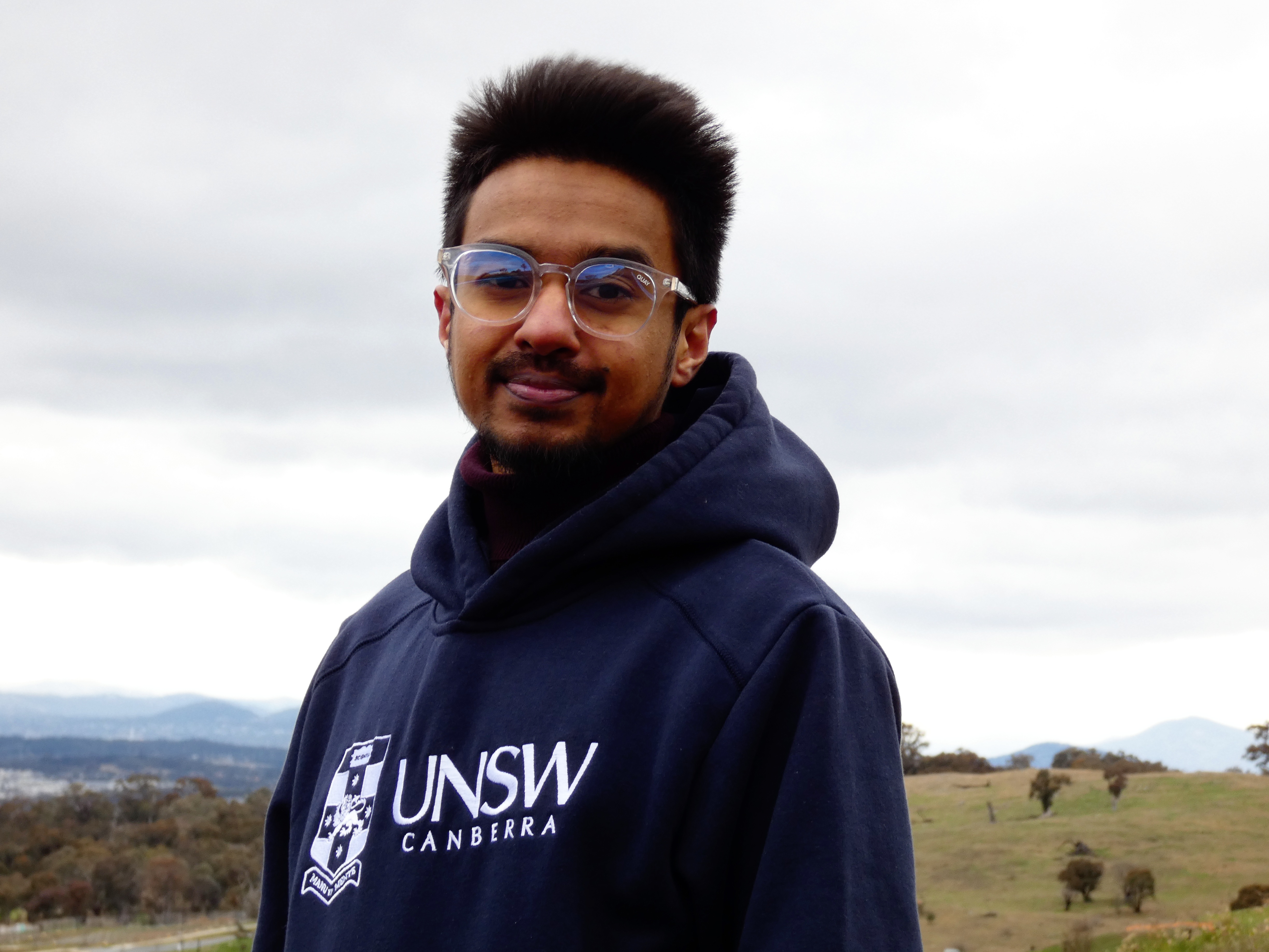 Photo of a man wearing a hooded jumper with the words UNSW Canberra