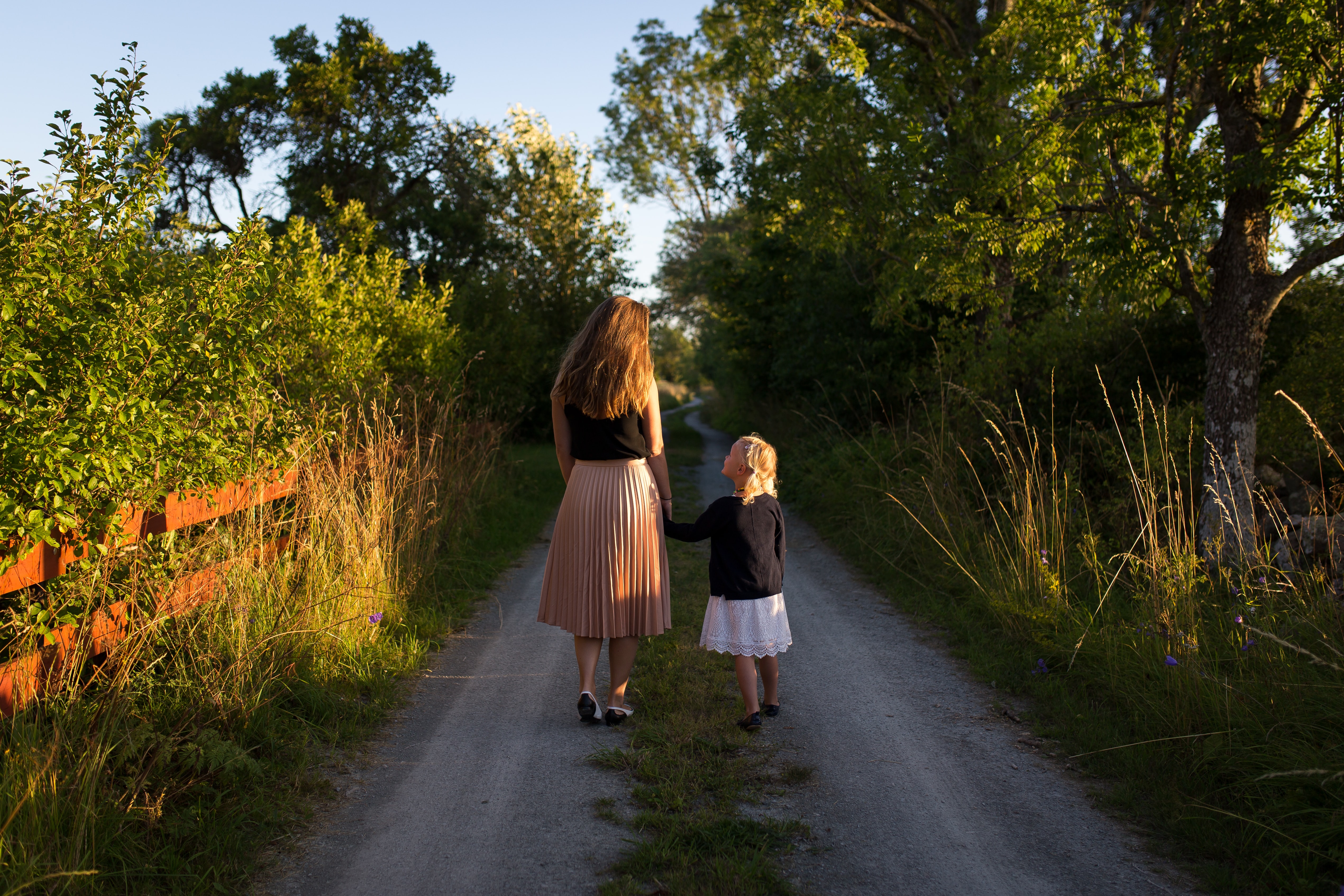 Woman and girl walking on road. 