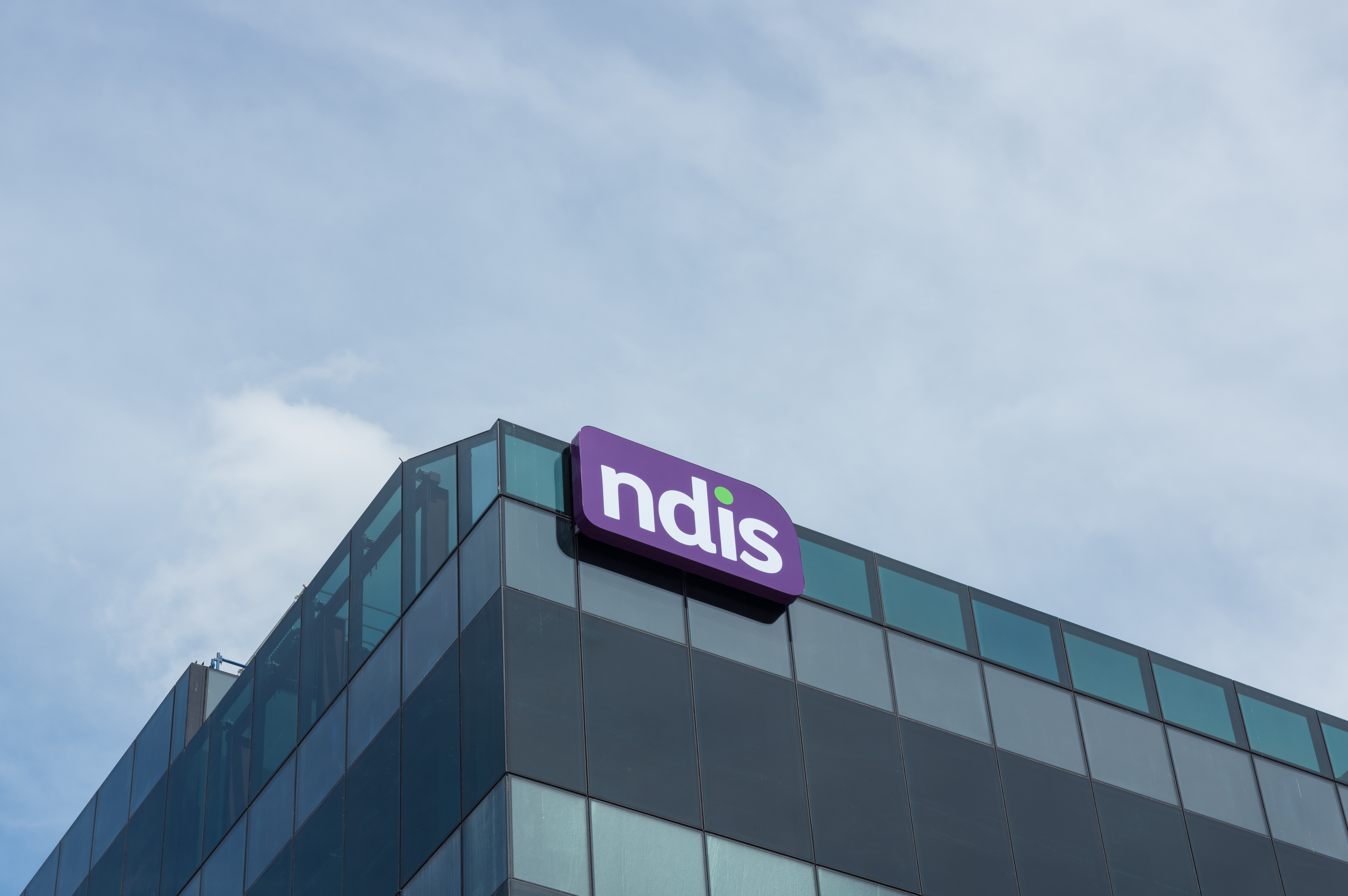 The top of a glass building with an NDIS logo