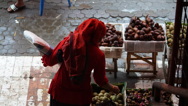 Woman in red robe gathering fruit at markets