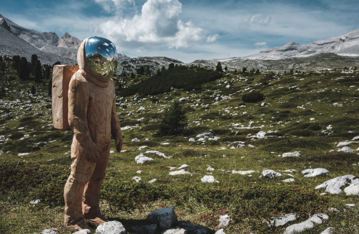 Astronaut stands in mountain landscape.