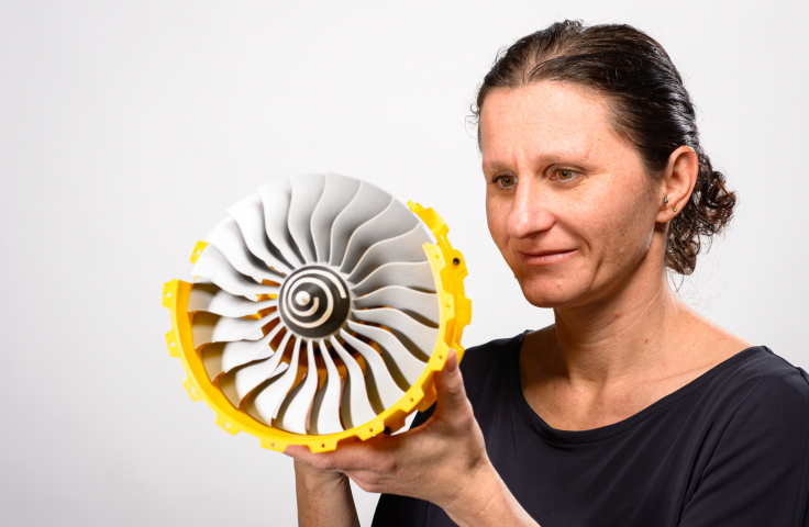 Bianca Capra holding a 3D printed prototype turbine engine
